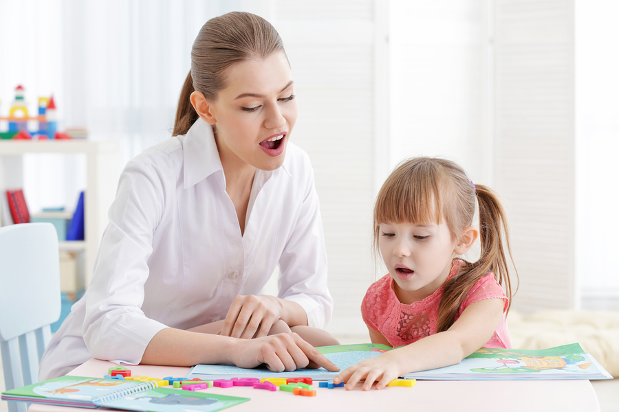 A speech pathologist and young child reading together and practising sounds
